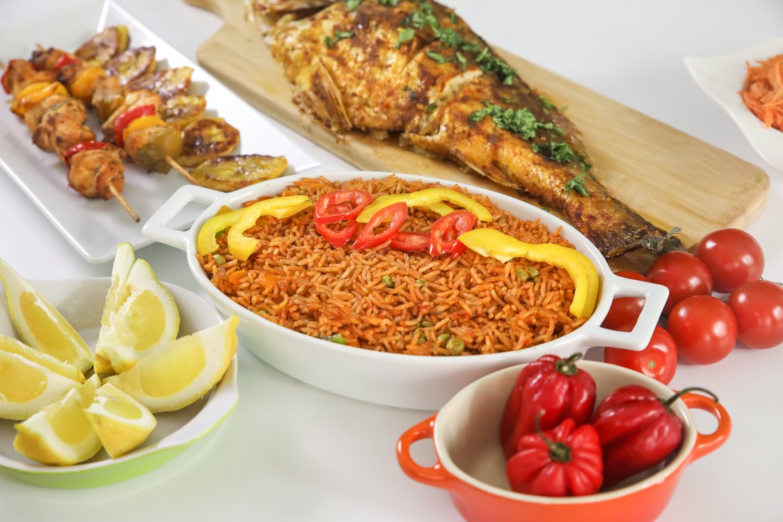 A plate of jollof rice with grilled fish, ready for collection